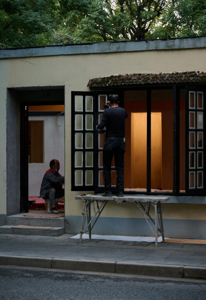Two workers engaged in home renovation, focusing on repairing windows outdoors.